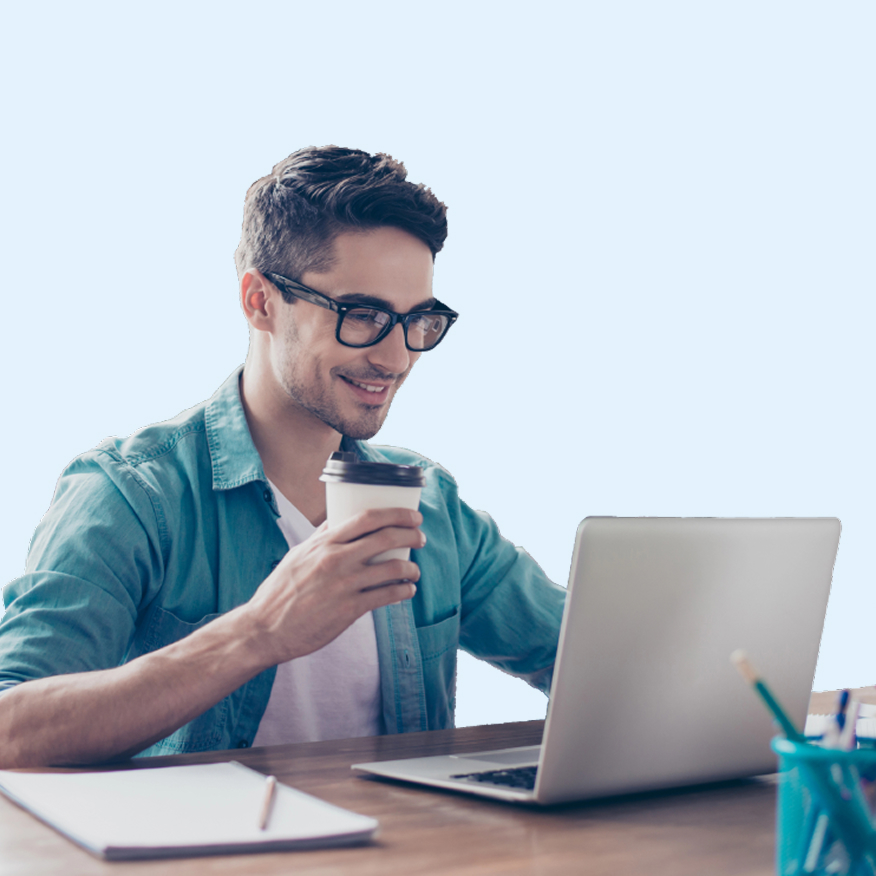 Male entrepreneur with glasses holding coffee and smiling at laptop open on desk.